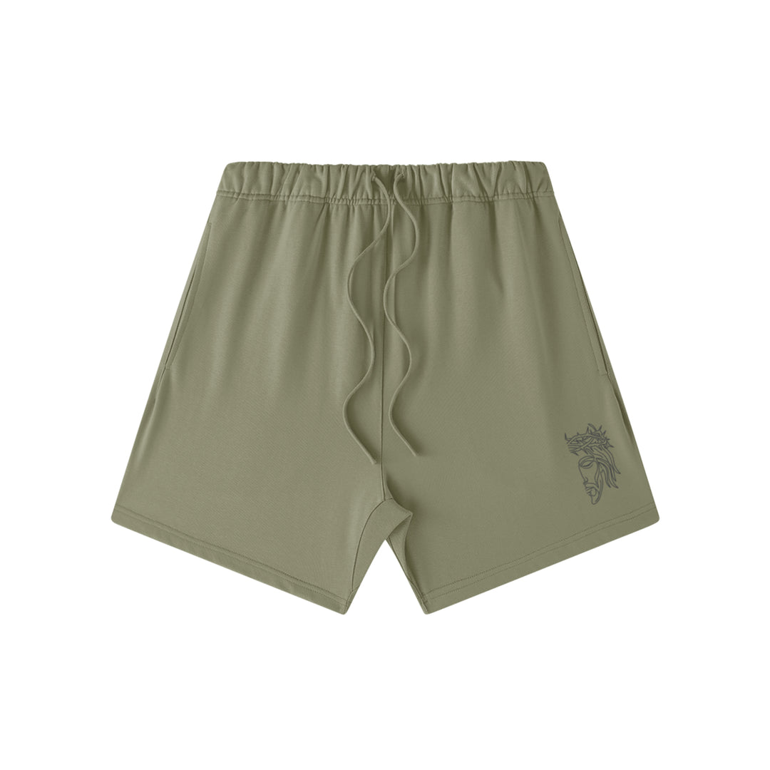 Front studio flat lay view of the Foundations Series Heavyweight Unisex Sweat Short in an artichoke green colorway. Features premium high-density Christ Half Face line-art embroidery on the left front leg panel, an overbuilt single-casing topstitched waistband with heavy-gauge tonal drawstrings, and a modern right-above-the-knee cut silhouette in massive 425GSM combed cotton French terry fabric.