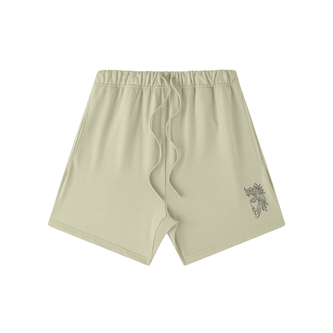 Front studio flat lay view of the Foundations Series Heavyweight Unisex Sweat Short in a pastel grey colorway. Features premium high-density Christ Half Face line-art embroidery on the left front leg panel, an overbuilt single-casing topstitched waistband with heavy-gauge tonal drawstrings, and a modern right-above-the-knee cut silhouette in massive 425GSM combed cotton French terry fabric.
