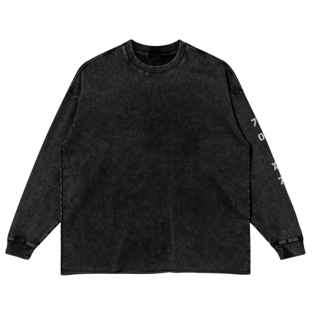 Front studio flat lay view of the Foundations Series 70X7 Raw Hem Long Sleeve in a sun-faded black tone, designed as premium Christian streetwear. Features a loose, boxy drop-shoulder silhouette in a heavy 260GSM combed cotton, highlighted by a weathered vertical stencil 70X7 sleeve print and a rugged raw-edge hem finish for a mission-driven Christian clothing statement.