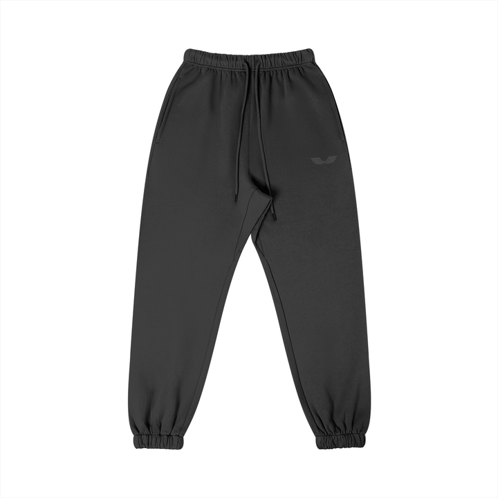 Front studio flat lay view of the Foundations Series Heavyweight Unisex Brushed Fleece Jogger in a black colorway, designed as premium Christian streetwear. Features a subtle tonal effect with high-density black Wings Emblem premium embroidery on the left thigh, an overbuilt single-casing comfort waistband with heavy-gauge cotton drawstrings and black metal aglets, and gathered ankle cuffs on a structural 380GSM combed cotton relaxed tapered canvas for mission-driven Christian clothing and apparel.