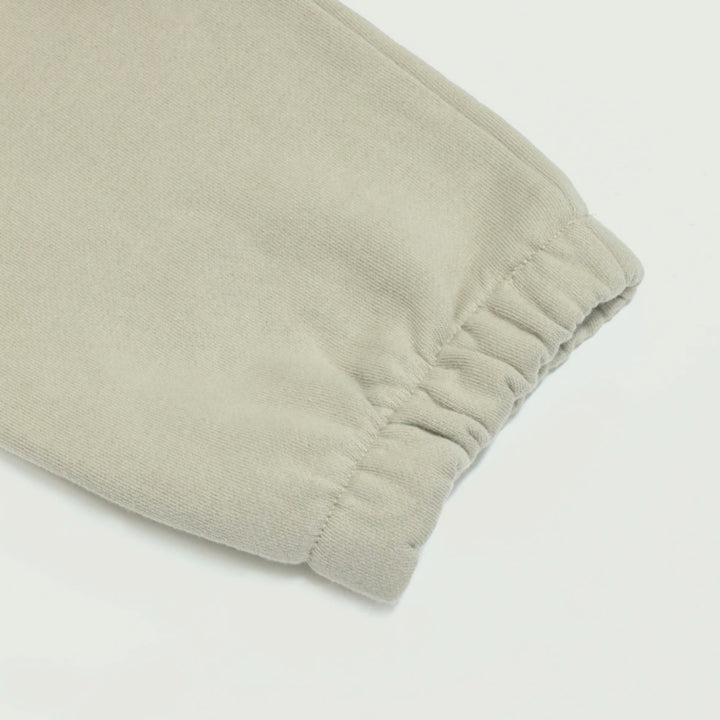 Macro detailing shot of the Foundations Series Heavyweight Unisex Brushed Fleece Jogger in a camel tone, optimized for high-intent Christian streetwear and clothing queries. Close-up tightly isolates the durable elastic ankle cuff gather, highlighting the dense structural grain and heavy pooling character of the 380GSM combed cotton fleece fabric.