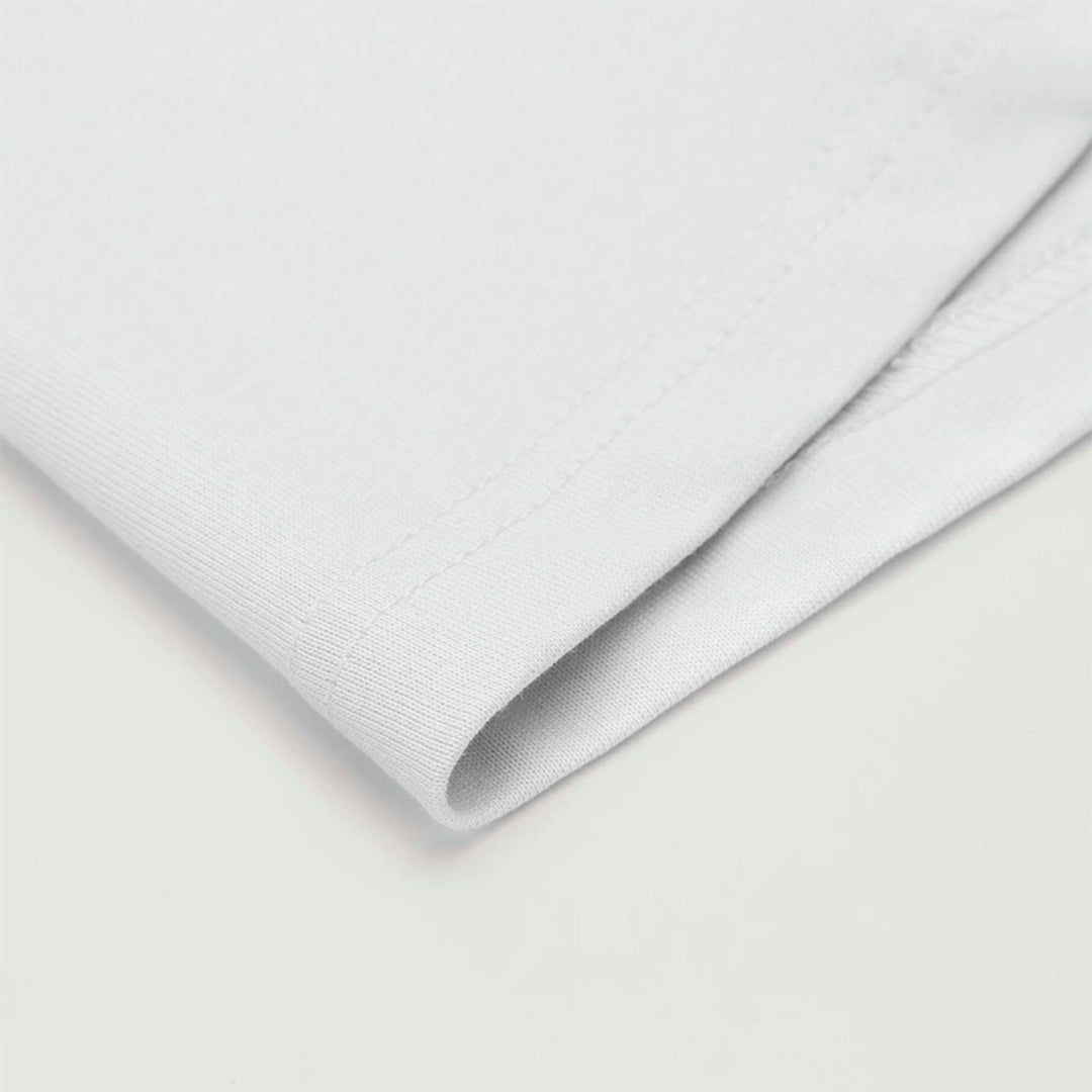 Macro detailing shot of the Foundations Series Unisex Embroidered Boxy Tee in white. Close-up tightly isolates the robust double-stitched bottom hemline, showcasing the structural premium knit structure, soft-touch brushed texture, and heavy drape of the 280GSM combed cotton fabric for a clean Christian clothing staple.