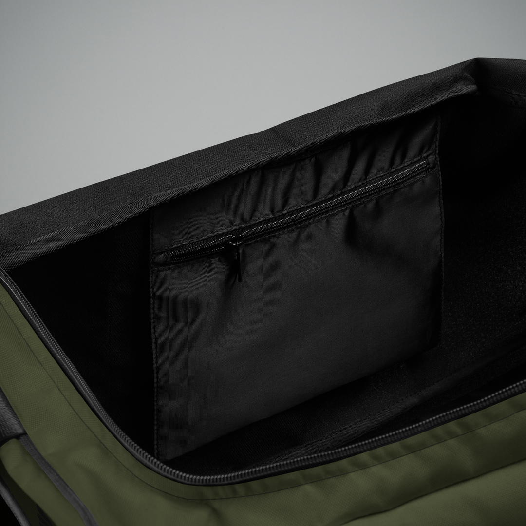 Interior view of the Foundations Series Let God Carry It Utility Duffle Bag in olive green. Open compartment showcases the secure, concealed internal zippered security pocket, protective black interior interlining, and spacious organization layout.